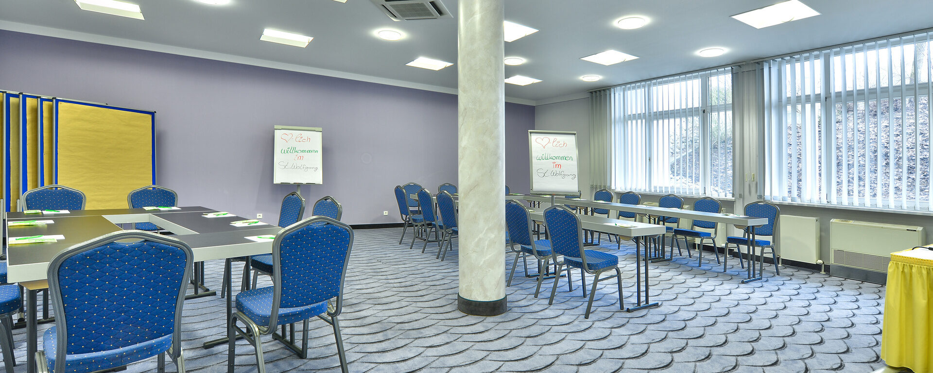 Blaue Stühle und praktische, schwarze Tische im Tagungsraum im Tagungshotel