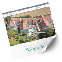 Luftaufnahme eines großen Gebäudekomplexes mit roten Dächern, der einen Pool umgibt, eingebettet in grüne Landschaft. Text: „Gäste A - Z / guest A - Z; Hotel ST. WOLFGANG.“