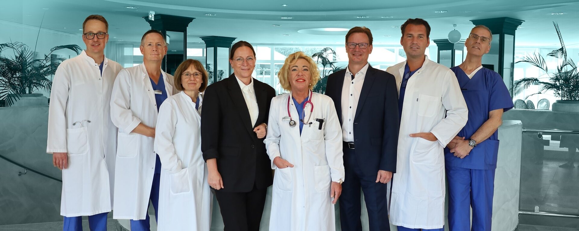Ein Ärzte- und Hotel-Team posiert zusammen in weißen Kitteln in einer Klinik. Ein Ärzteteam steht für ein Foto bereit.