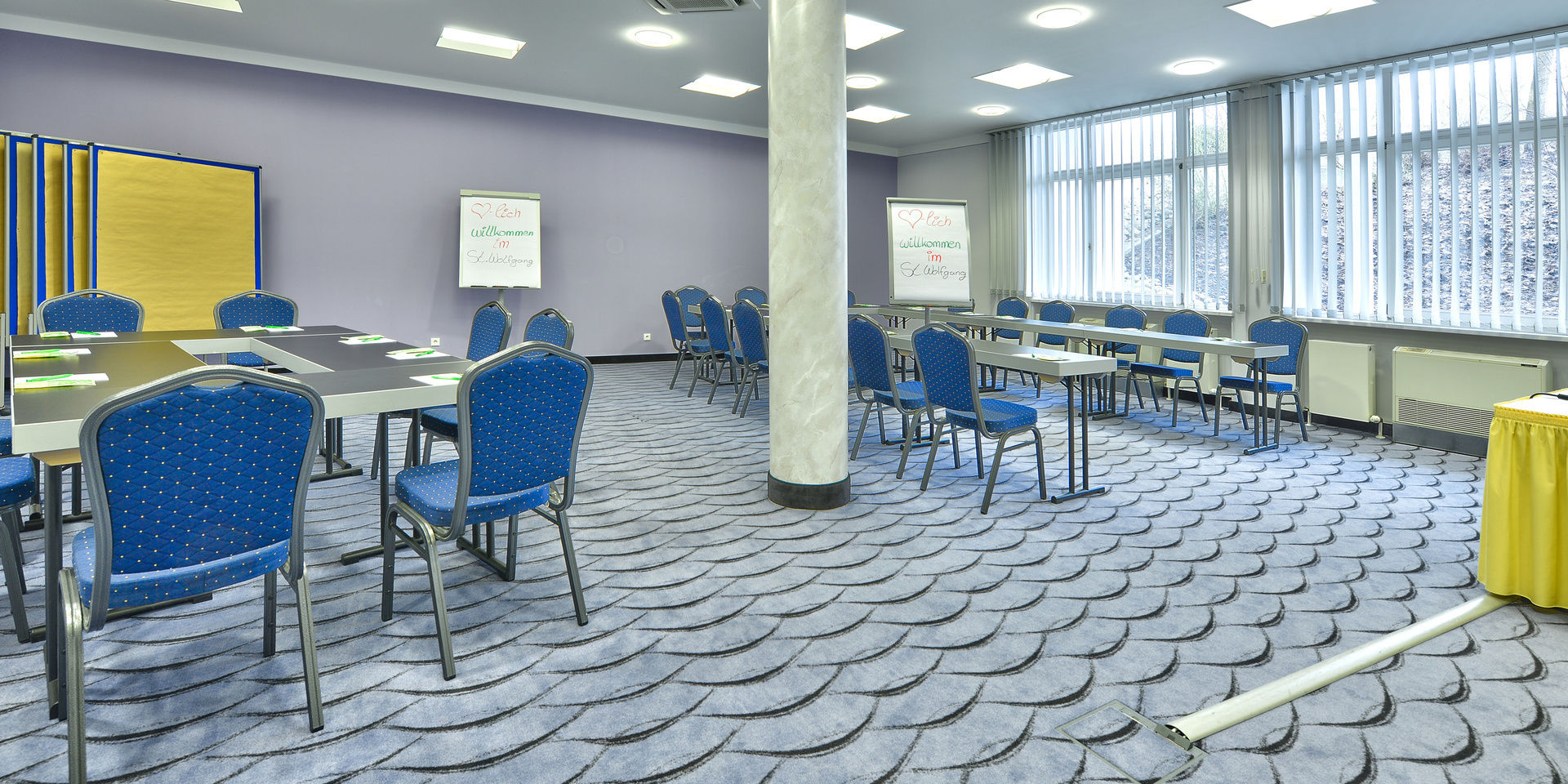Blaue Stühle und praktische, schwarze Tische im Tagungsraum im Tagungshotel