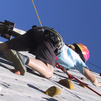 Frau klettert auf einer Kletterwand im Rahmen einer Tagung im St. Wolfgang