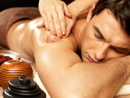 Dame massiert Mann mit Öl auf dem Massagetisch im St. Wolfgang